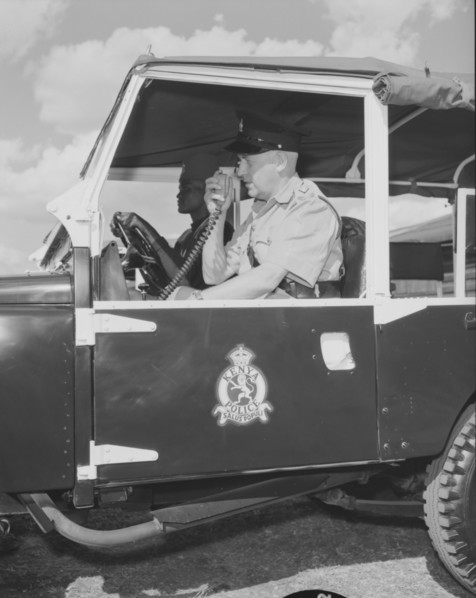 Kenyan police jeep. A uniformed policeman sits inside a police jeep operating a radio receiver