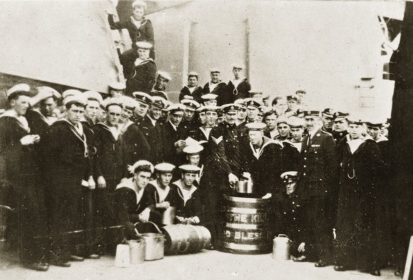 Barrel of rum. Uniformed naval personnel aboard HMS Repulse pose for a group portrait around a