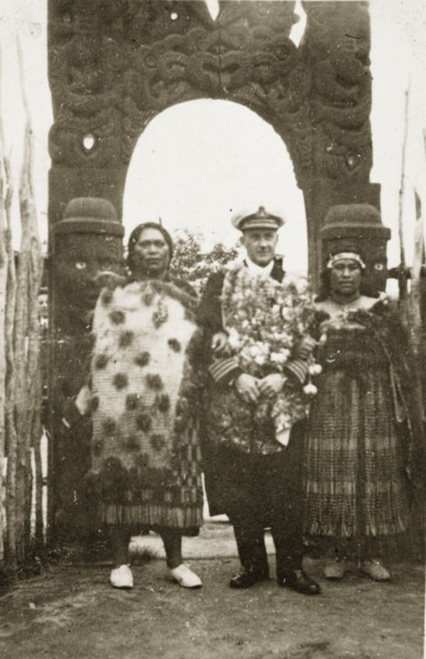 Rear Admiral Brand visits a Maori arch. Rear Admiral Sir Hubert Brand stands between two Maori