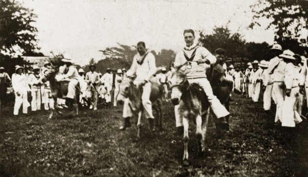 Donkey derby winning post. Uniformed sailors in the British Special Service Squadron entertain