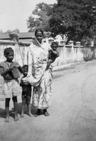 Indian woman with children. An Indian woman dressed in a sari stands, baby on hip, beside two