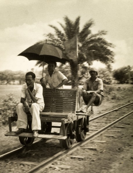 Railway hand cart. Three men sit aboard a small railway cart fitted with a wooden seat, an unusual