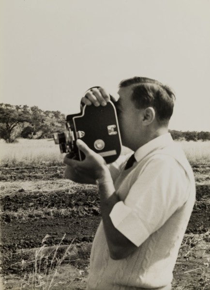 Filming for the Central African Film Unit. A European cameraman operates a movie camera during a