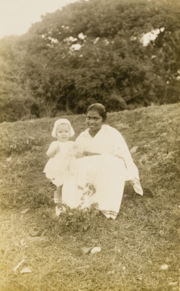 Ayah with toddler. Outdoors portrait of a young British toddler, posing for the camera with her