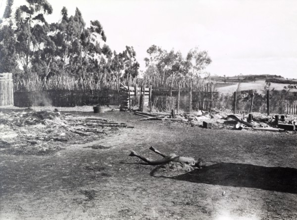 Child murdered by Mau Mau. The body of a murdered child lies rigid in the smoking ruins of a