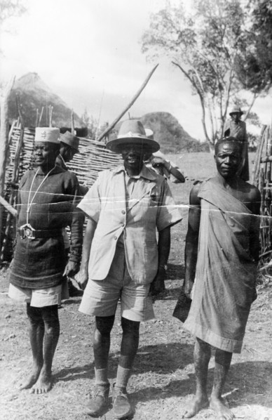 Mau Mau suspect and guards. A Mau Mau suspect under arrest is guarded by two men who stand either