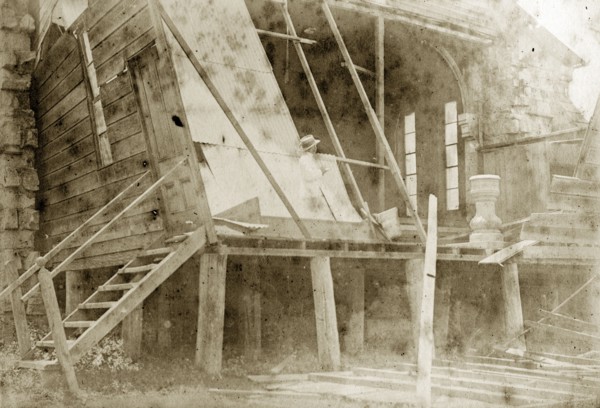 Destruction of a temporary church. A man takes notes inside the ruins of a wooden church