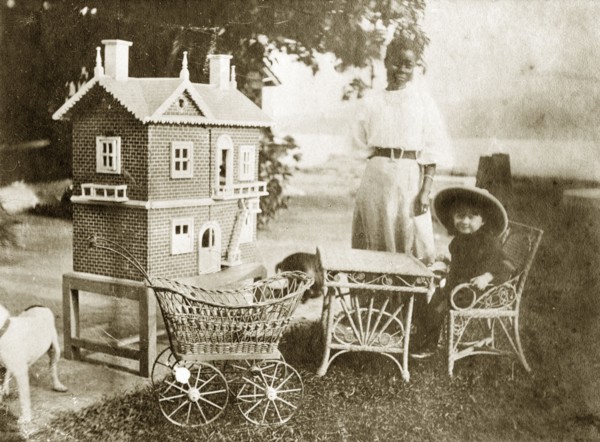 Marjory Wood's dollhouse. A young girl identified as 'Marjory Wood' sits at a miniature table