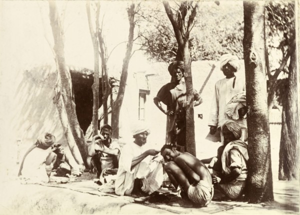 Indian street barbers. Turbaned Indian men sit on rugs in the street, providing a barber service