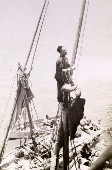 A 'gully gully' man. An Egyptian 'gully gully man' (travelling magician), perches high on the mast
