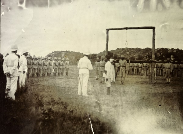 Governor reads death sentence. A European official reads a death sentence, facing a large wooden