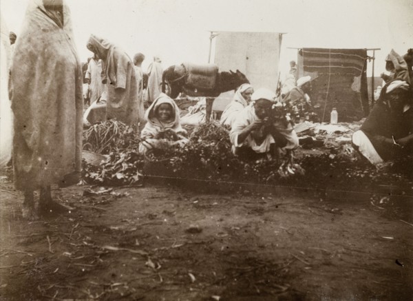 Market scene, Casablanca. Street traders crouch on the ground, trying to sell fruit and vegetables