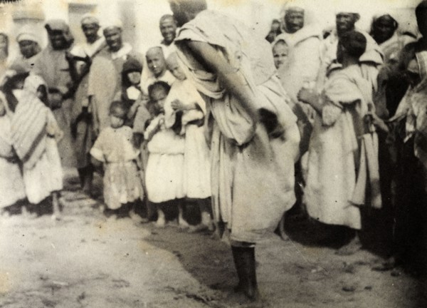 Storytelling at Safi. A 'halaiqui' (storyteller) hops on one leg as he entertains a 'halca'