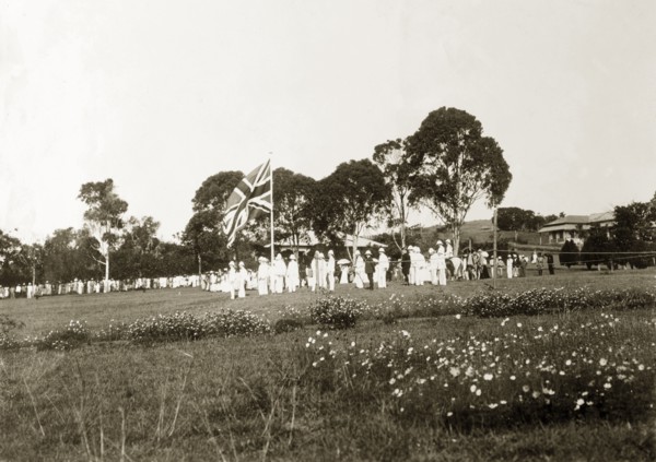 The King's birthday reception. A union jack flag, surrounded by men in white uniforms, flies high