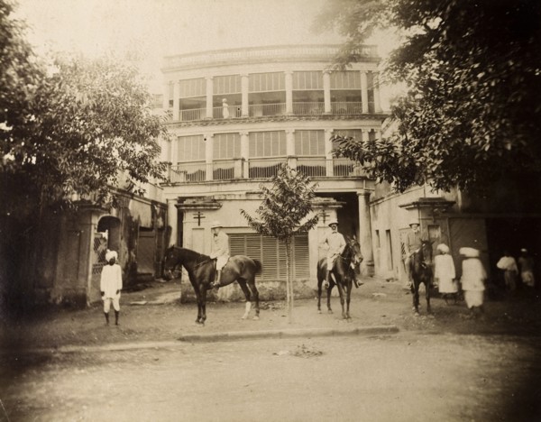 Saddling up outside a colonial house. S.A.H. Sitwell and friends pose on horseback in the walled