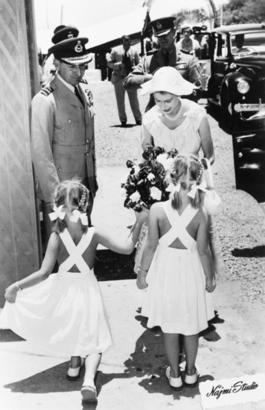 Queen Elizabeth II presented with flowers by two girls in Aden, 1954. Two young girls present a