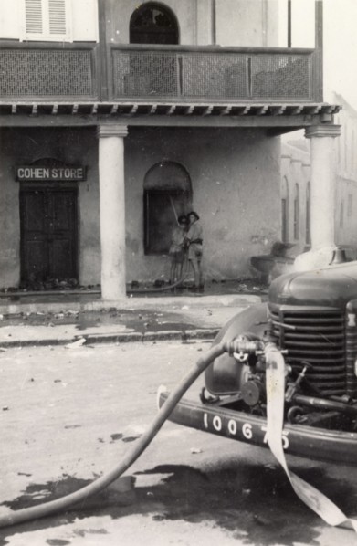 Fire fighters in Aden during the Arab riots, 1947. Two fire fighters extinguish a fire in 'Cohen