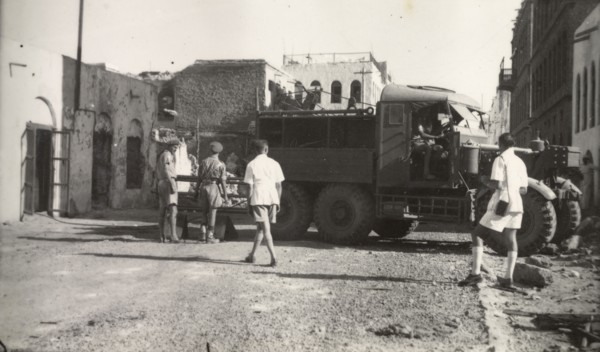 Clearing up after Arab riots in Aden, 1947. Soldiers maneuver a utility truck through a street in