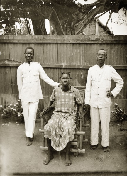 Portrait of domestic servants. Portrait of two male domestic servants and a woman in a garden.