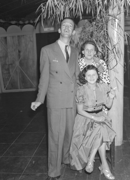 Guests at a Christmas party. Mr and Mrs Morris pose for the camera with Mrs Holmes at a Christmas