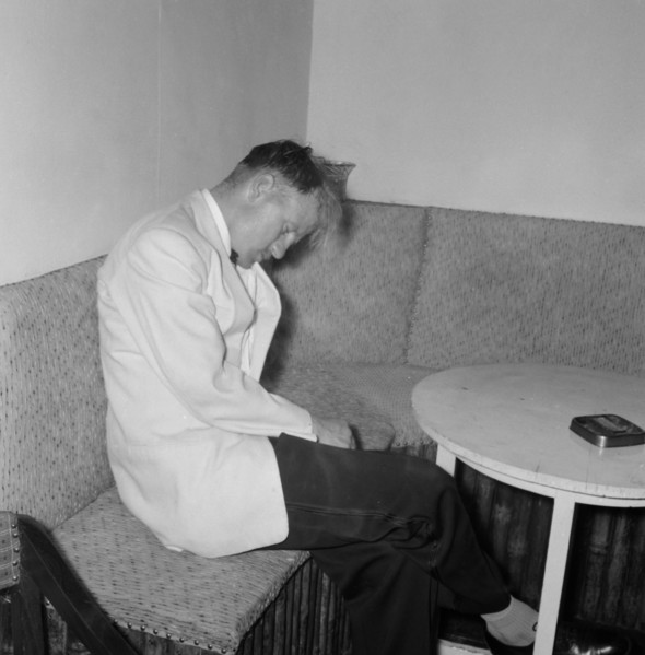 Worse for wear. A formally dressed man looks the worse for wear as he nods off in corner during a