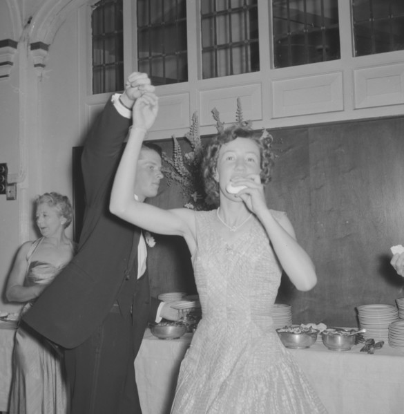 Dancing at the Limuru Hunt Ball. A young woman dressed in evening wear eats with one hand as she is