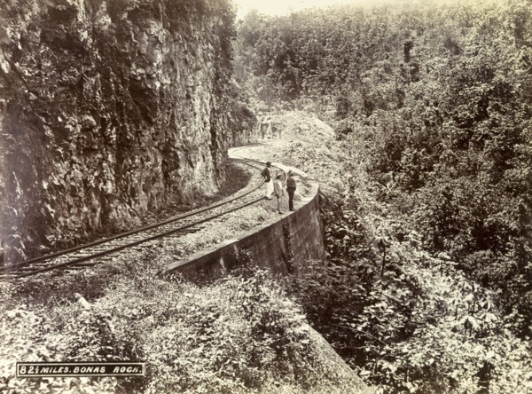 Railway track at Bonas Rock. Three men stand on a stretch of railway track that clings to the side