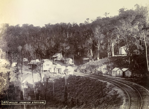 Ipswich railway station. Wooden buildings constructed on cleared forest land surround the track at
