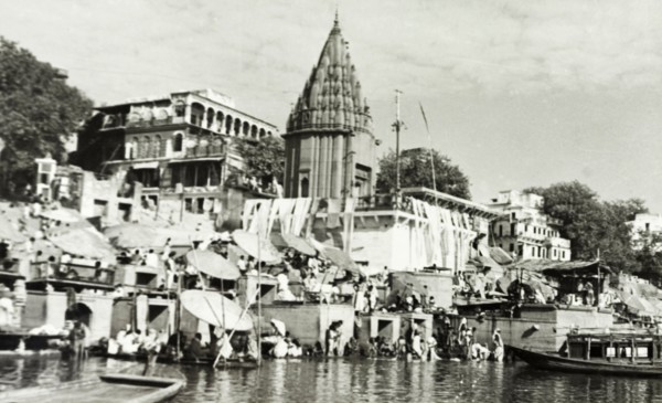 Hindu temple at Benares. Religious pilgrims sit beneath large umbrellas at a ghat (stepped wharf)