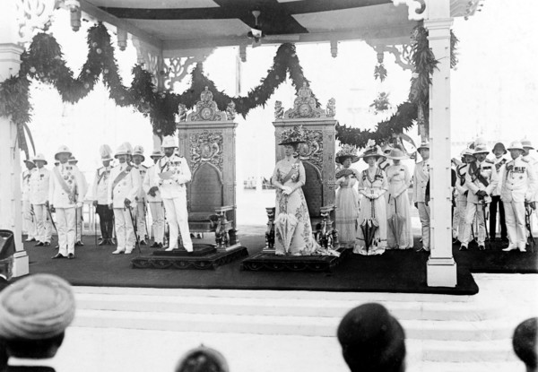 King George V arrives in Bombay. King George V (r.1910-36) and Queen Mary stand before a pair of