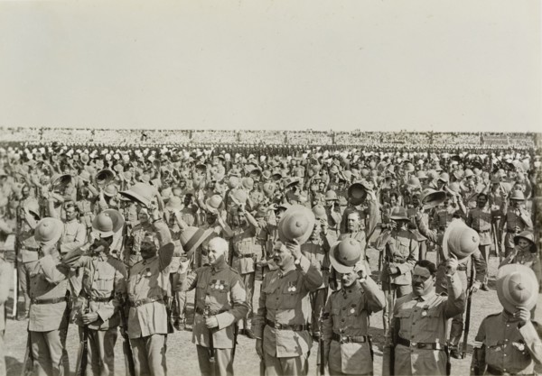 Three cheers for King George V. Numerous lines of uniformed soldiers stretch into the distance,