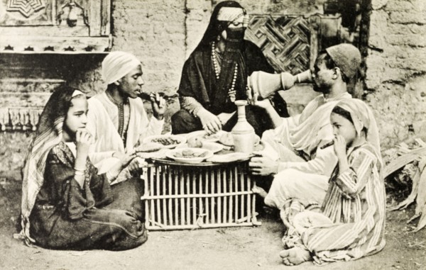 A familiar dinner'. A posed portrait depicting a 'typical' Egyptian meal. A veiled woman adorned