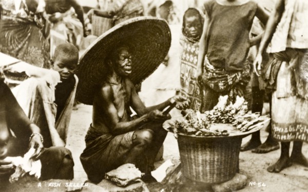 Fish seller, Gold Coast. An elderly woman dressed in a huge, wide brimmed hat, sells fish to