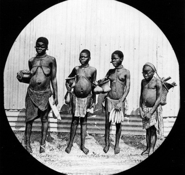 Four African women. Group portrait of four semi-naked women, each carrying a basket filled with