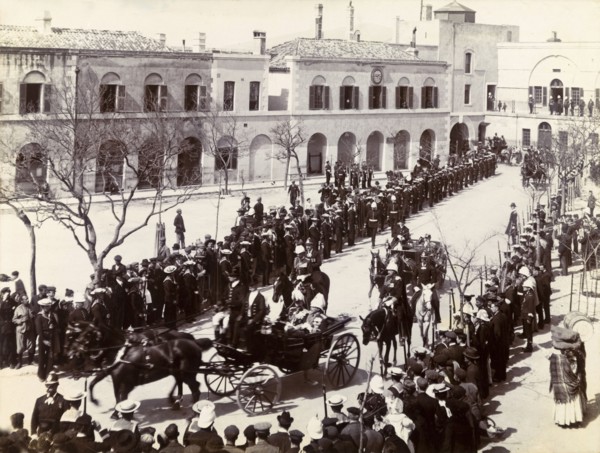 Procession in Gibraltar. Two distinguished gentlemen are driven through crowds gathered in a town