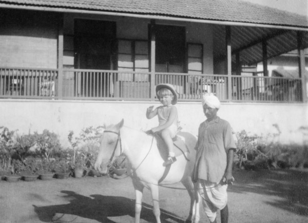 Adam rides a pony, Bombay. A British boy called Adam waves to the camera as he rides a pony in the
