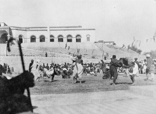 Wrestling match in Sukkur. A number of wrestlers fight each other in front of seated spectators