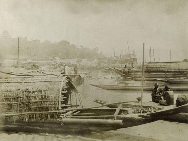 Boats on the Irrawaddy River. Several covered fishing boats are moored along a sandy bank of the