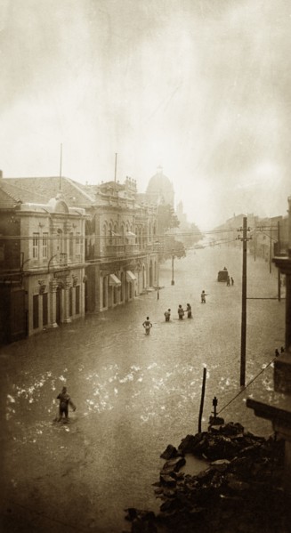 Flooded street in Karachi. A small band of people wades towards a partially submerged vehicle along