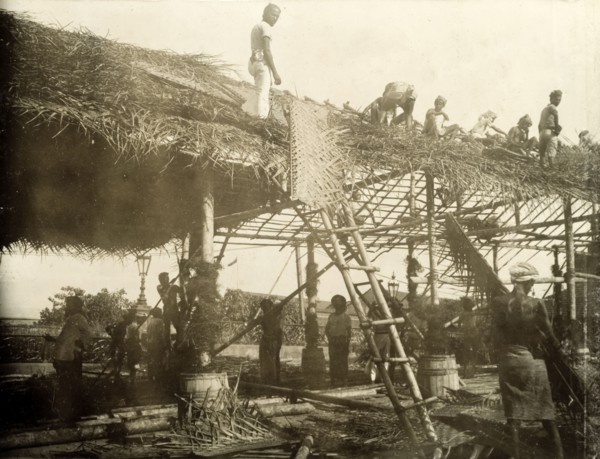 Thatching a roof for the royal visit. A team of Ceylonian men thatch the roof of a spectator stand