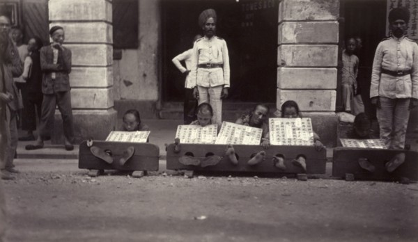 Petty criminals in the stocks, Hong Kong. A group of petty criminals sit with their ankles