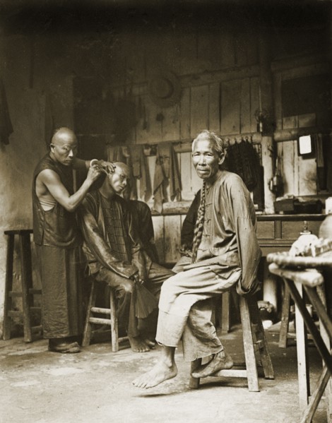 Ear cleaning at a barber's shop, China. A man sits on a stool to have his ears cleaned at a