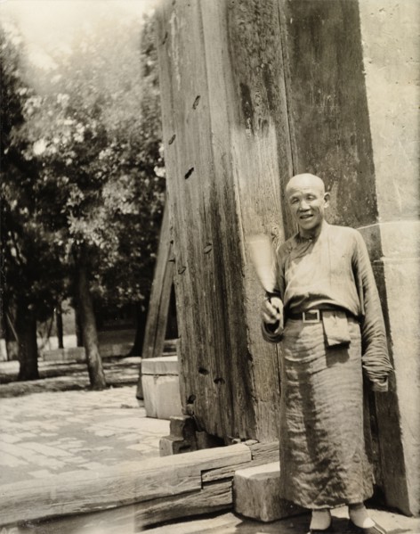 Lama priest at the doorway to a temple. A 'lama' (Buddhist monk) stands at the entrance to a temple