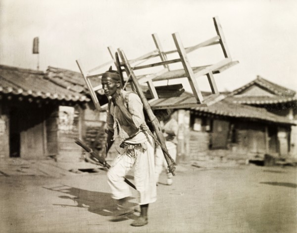 A Korean labourer carries a bench. A Korean labourer carries a wooden bench strapped to his back