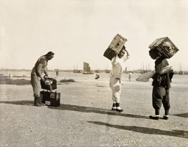 Luggage handlers at Newchwang port. Three luggage handlers prepare to load suitcases onto a waiting