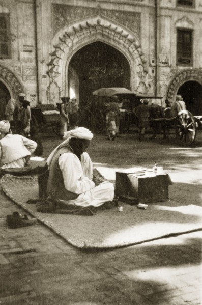 Letter-writing service. A street trader offering a letter-writing service sits on a rug on the