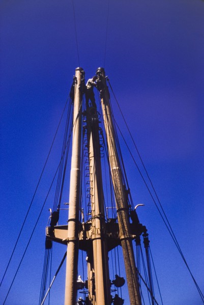 Sailor on the mast of M.V. Obuasi. A sailor stands at the top of a ladder on the stern mast of a