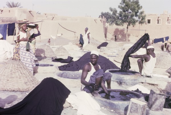 Indigo dyeing at Kano. Female hawkers circulate amongst textile workers who sit outdoors, dipping