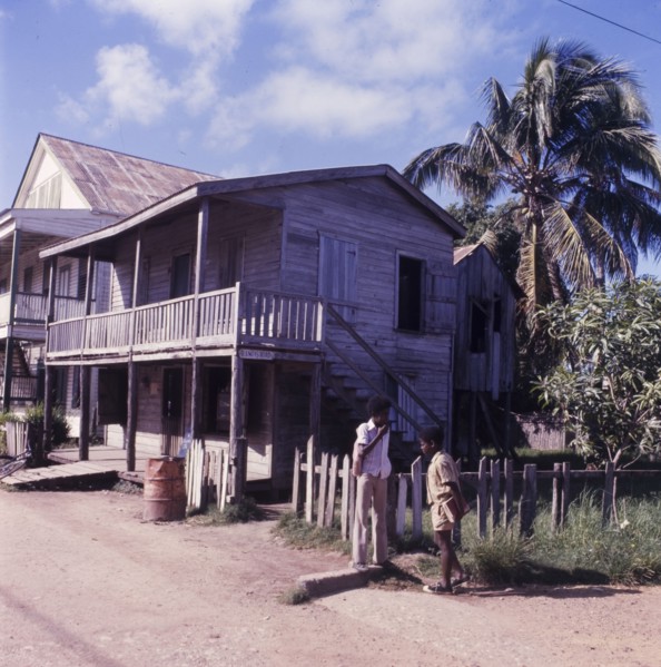 Wooden house in Belize. Two boys chat on a street corner outside a wooden, two-storey house in