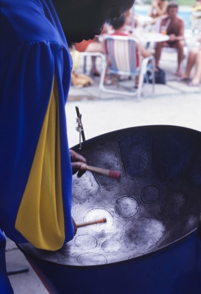 Barbadian musician playing steel drum. A Barbadian musician bows his head over a steel drum as he